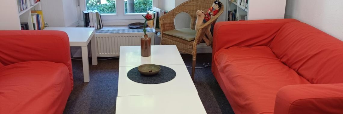 2 rote Sofas mit einem weißen Couchtisch
